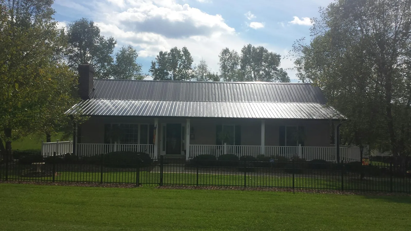 Gray metal roof on a brick ranch with a full width front porch — Gutter Guard Installation work by our crew in Kellogg
